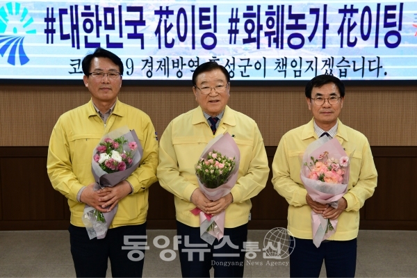 홍문표(홍성·예산) 국회의원의 지목을 받은 김석환 홍성군수(가운데)가 지난 7일 꽃다발을 안고 ‘부케 챌린지’에 동참했다. (사진=홍성군 제공)